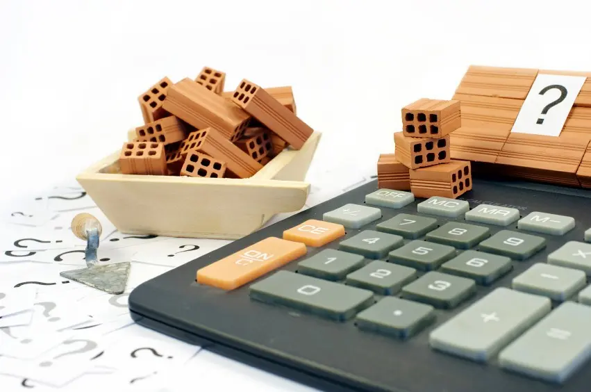 Calculadora y planos que representan el impacto de la mano de obra en los costos de construcción