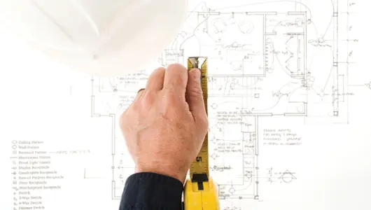 Persona revisando planos, ilustrando métodos para calcular los costos de construcción