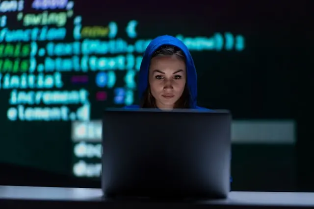mujer con capucha frente a una laptop