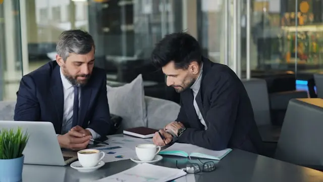 dos hombres en un escritorio viendo un grafico