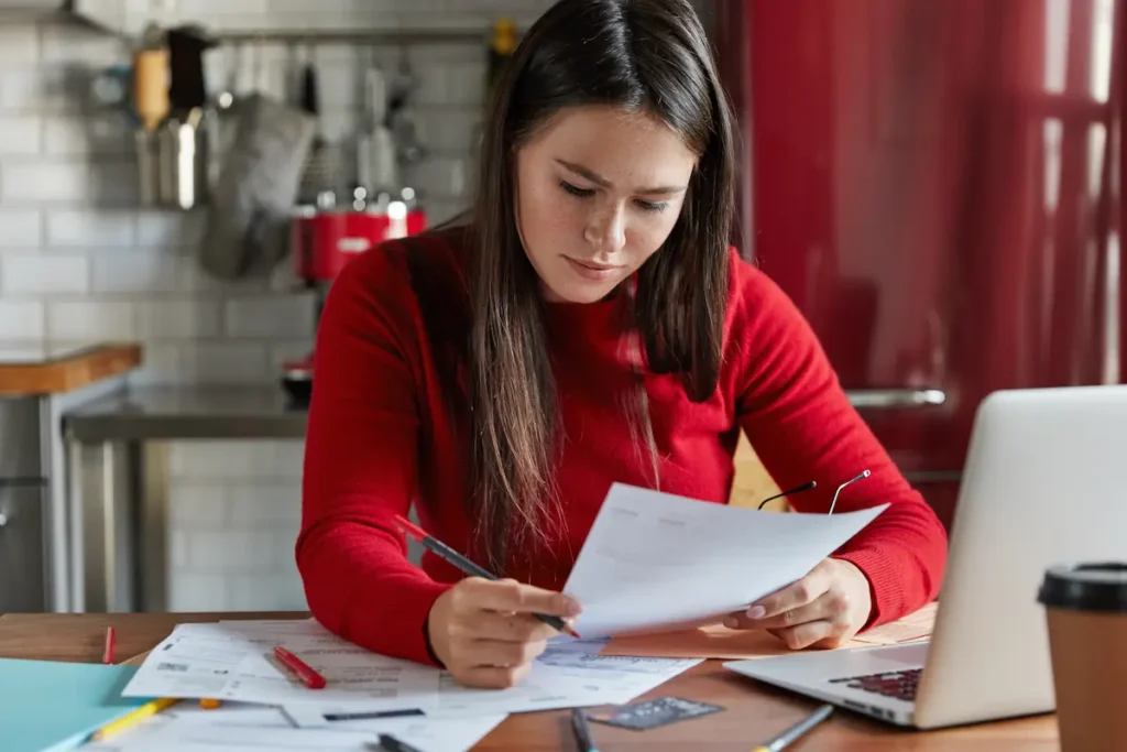 Trabajadora estudia análisis de mercado, hace pronósticos financieros, posa en el lugar de trabajo con documentación.